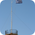 Flaga grecka powiewająca nad dawną twierdzą wenecką